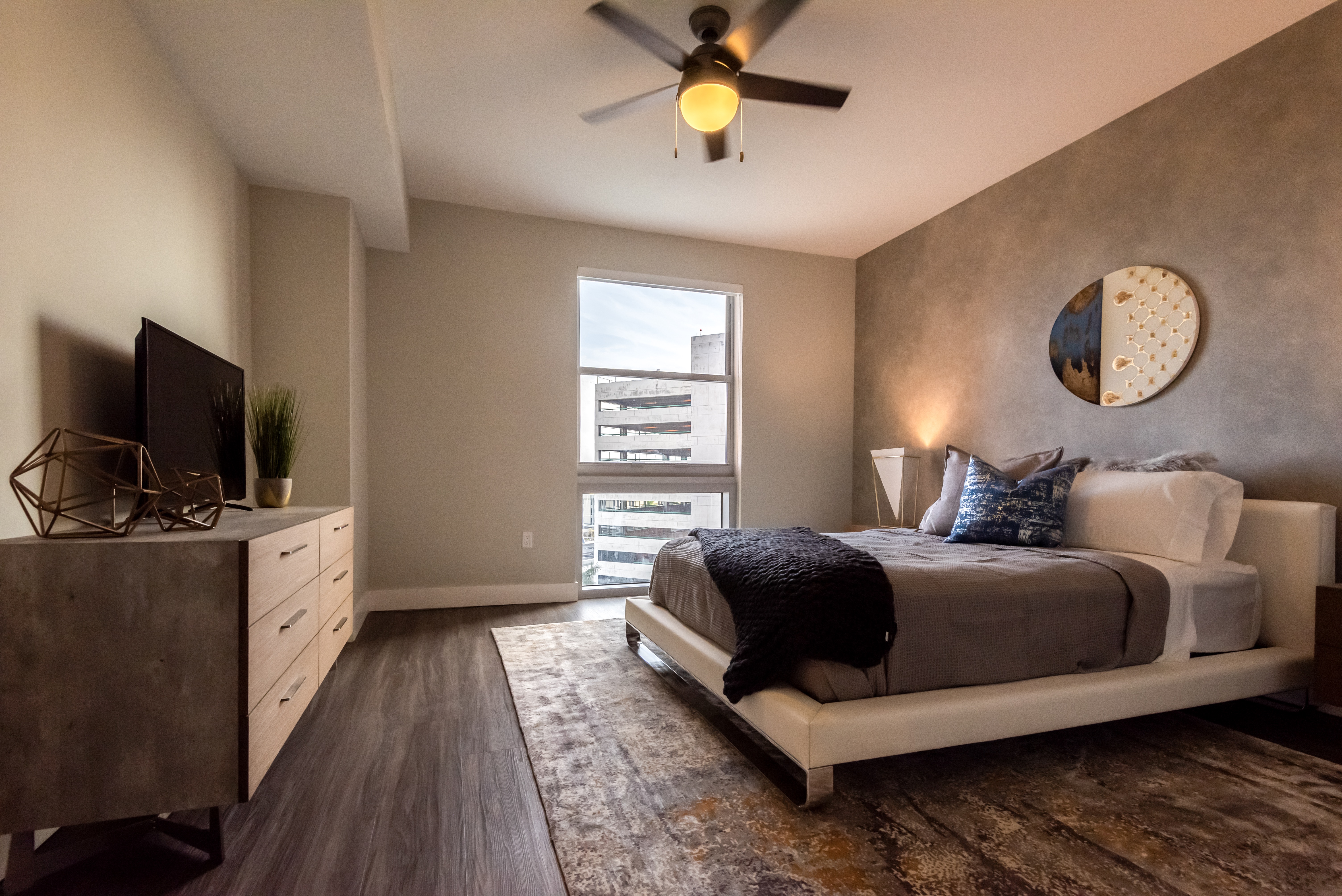 Modern apartment bedroom with king sized bed and ceiling fan