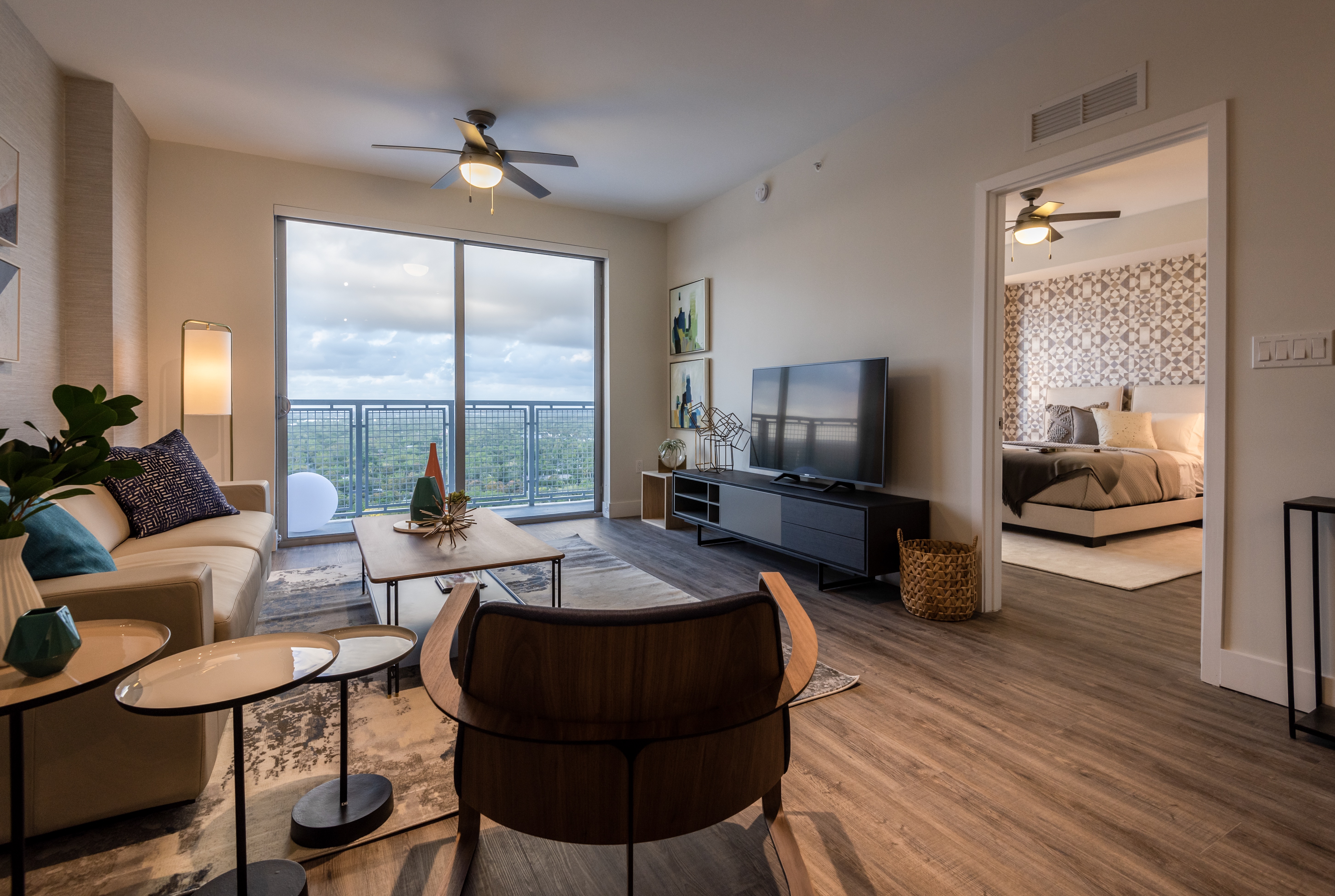 Apartment living room with hardwood floors, balcony view and bedroom