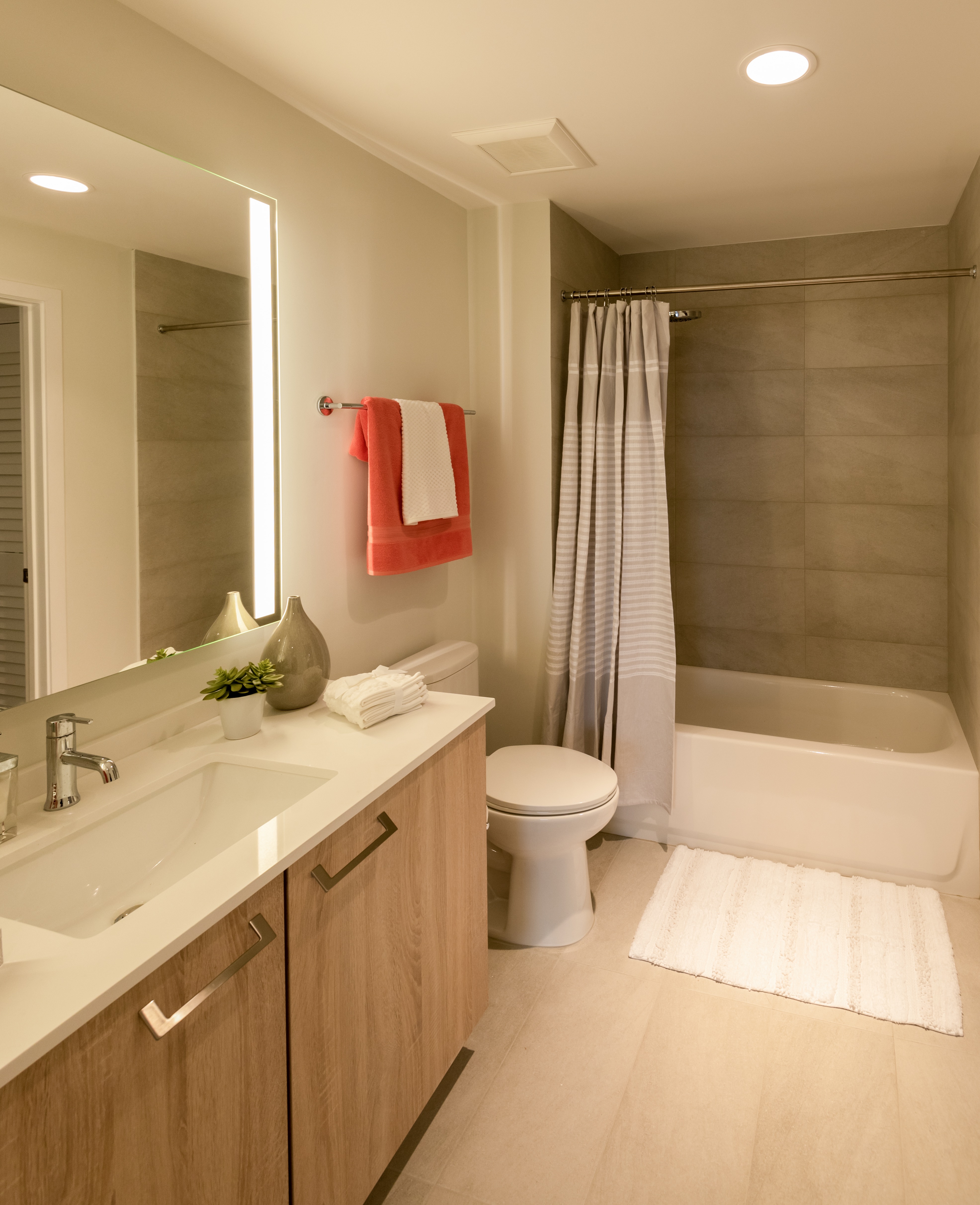 Modern beige full bathroom with tub, toilet and vanity