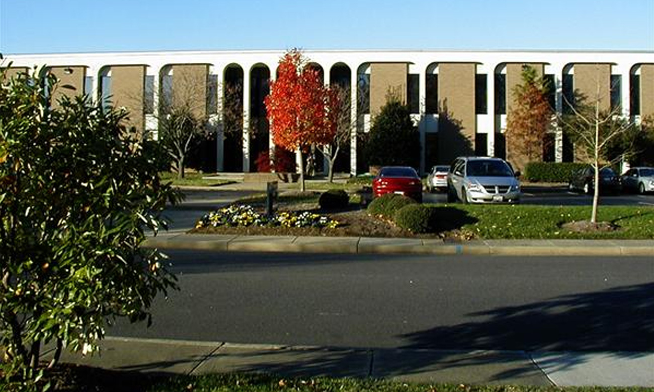 Office building with parking lot and fall foliage.
