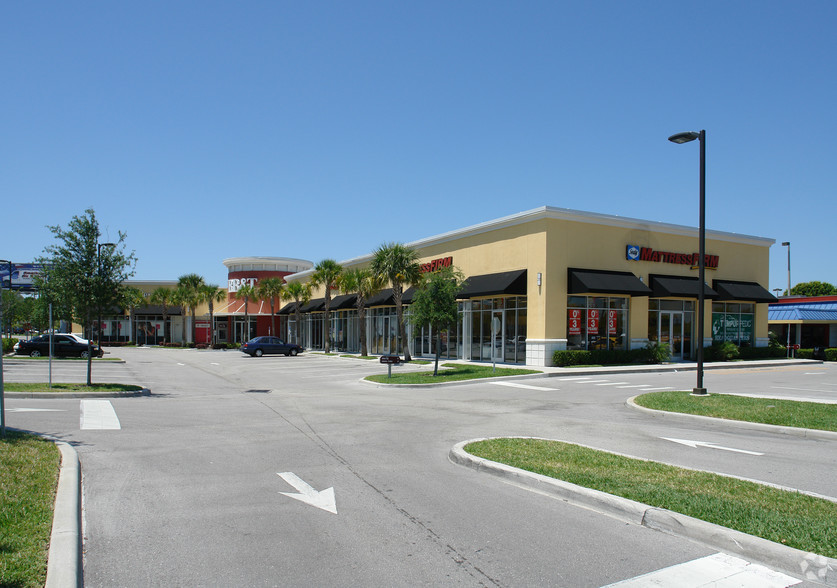Shopping center with palm trees, parking lot, and various businesses.